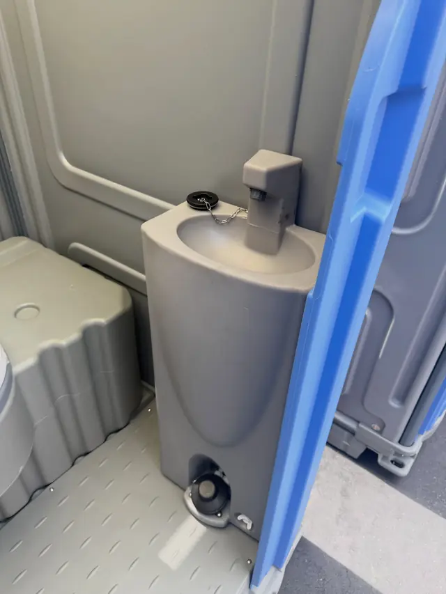 Foot-pump hand sink inside a portable toilet next to the toilet