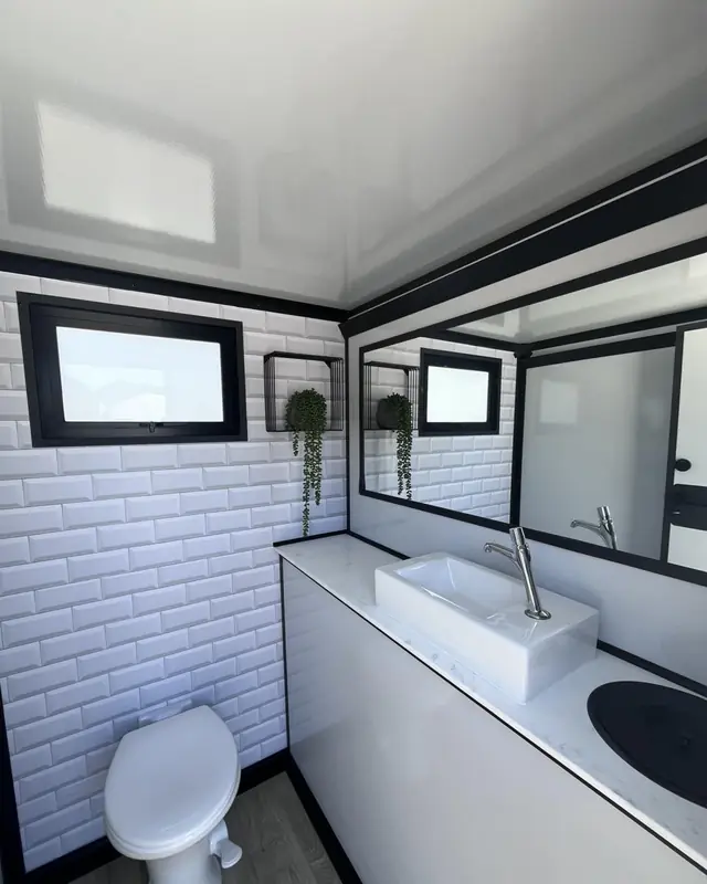 White tile-look restroom trailer stall with toilet and sink