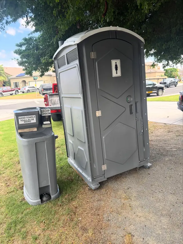 Portable toilet with a hand-washing station on a lawn
